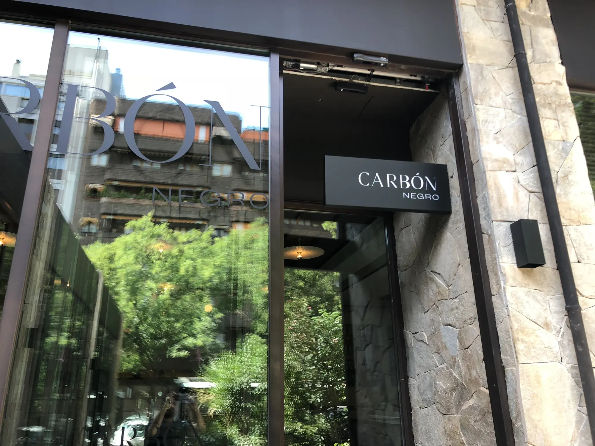 Rótulo corpóreo del restaurante Carbón Negro sobre la fachada de piedra