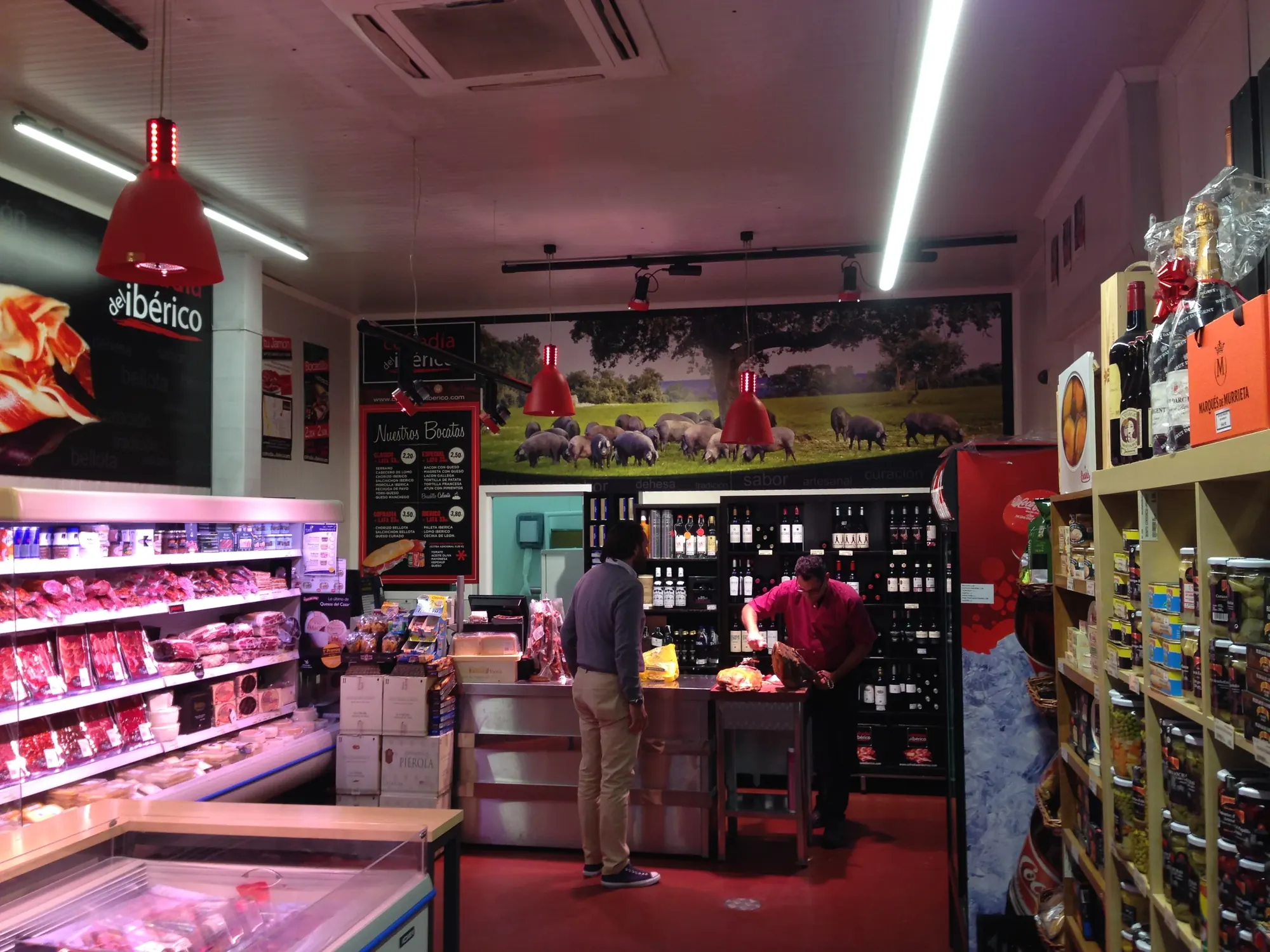 Interior de La Cofradía del Ibérico con el mural impreso de la dehesa sobre el mostrador