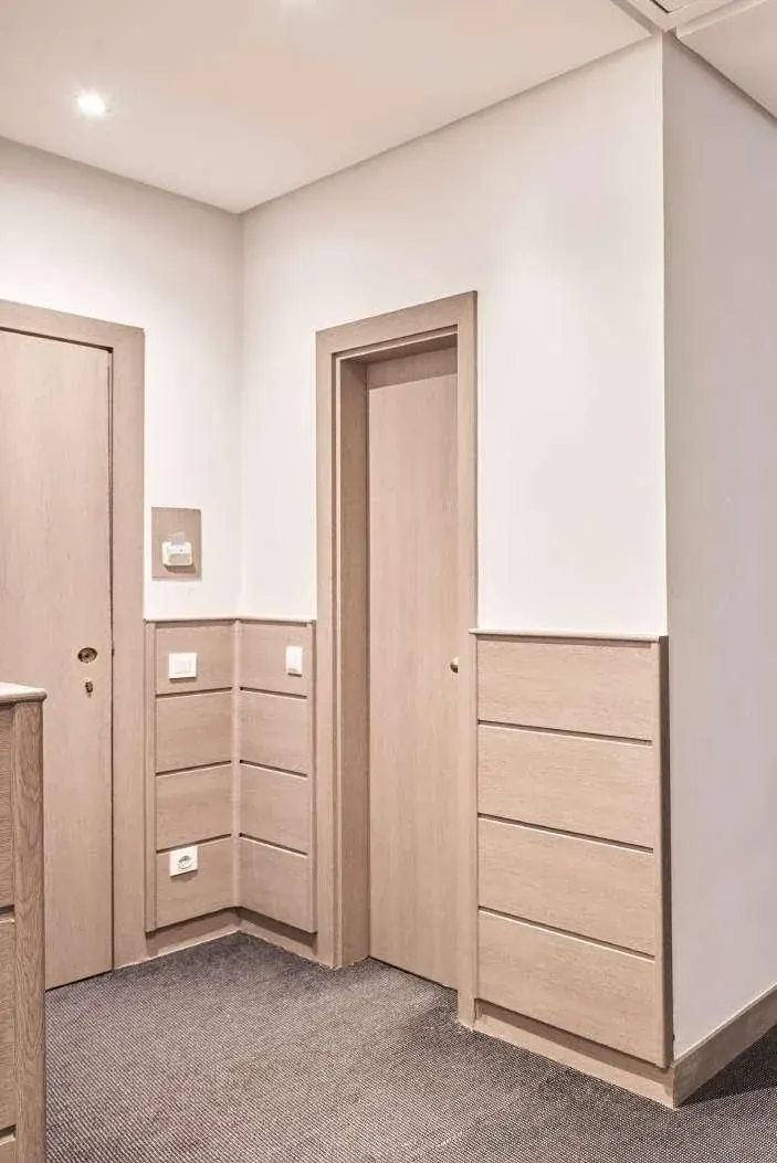 Pasillo de habitaciones con puertas, marcos y frisos revestidos en efecto madera